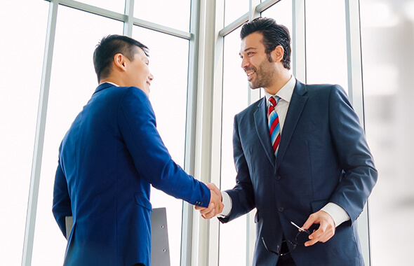 2名のスーツを着た男性がにこやかに握手している様子